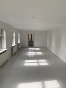 Lyst tomt rum med hvide vægge og trægulv