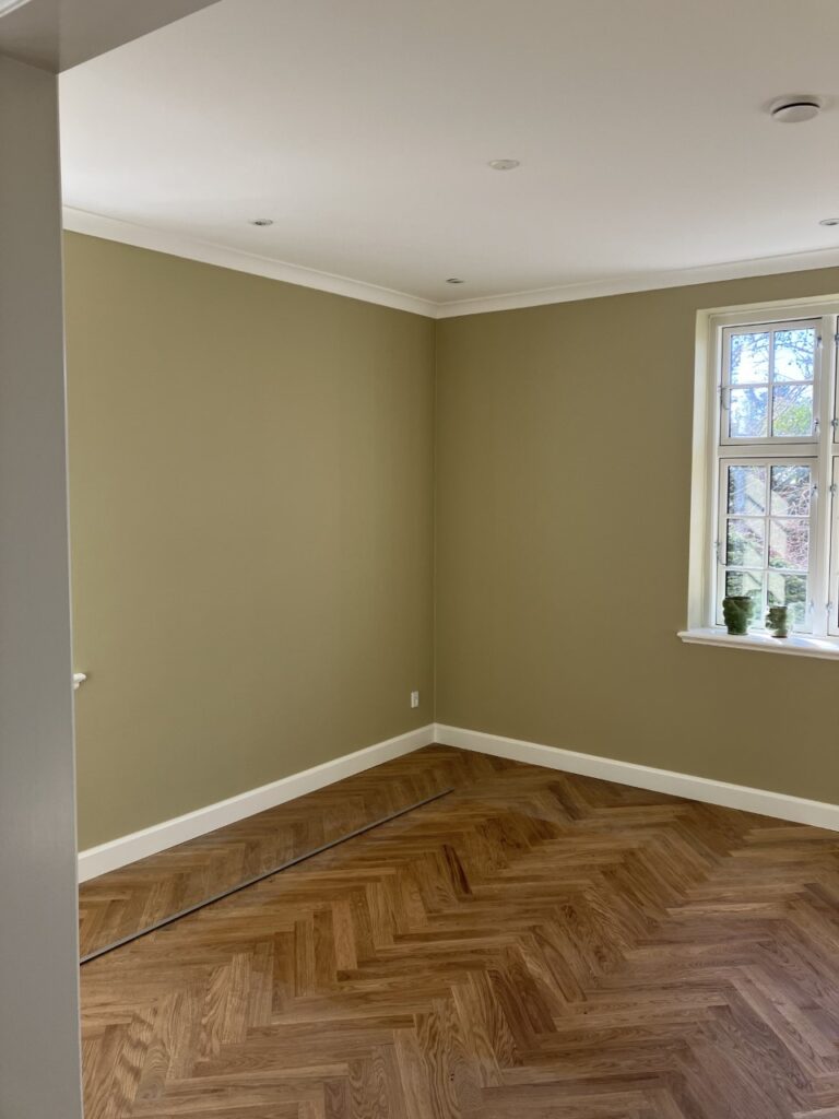 Lyst tomt rum med parketgulv og vindue